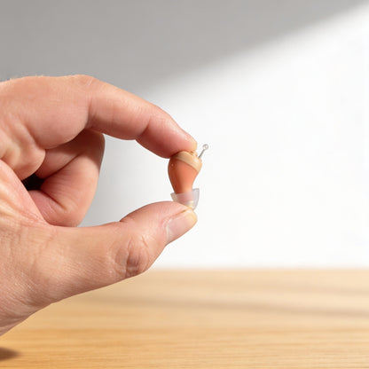 Clarity Pro Micro CIC hearing amplifier held between fingers showing compact size